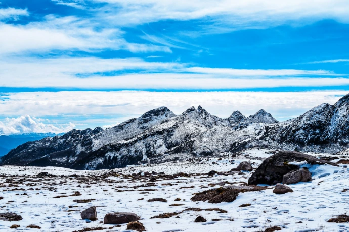 a mountain range covered in snow under a blue sky